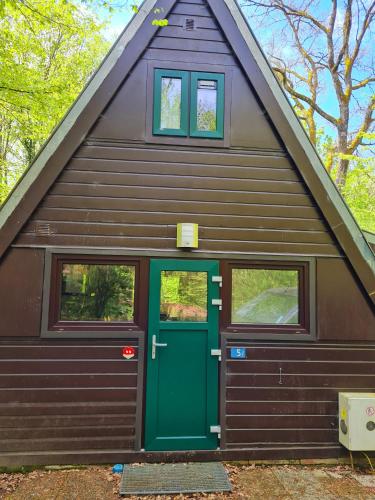 a garage with a green door and two windows at Chalet d Ooghe in Durbuy