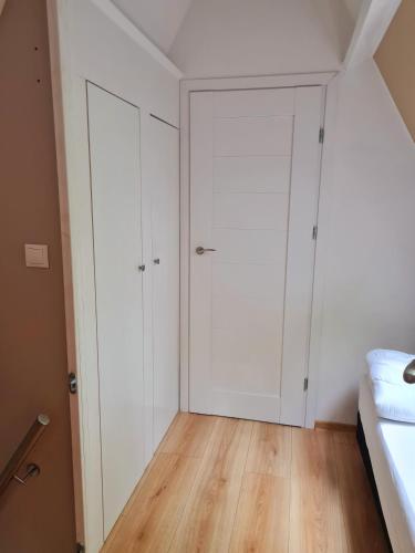 a bedroom with white cabinets and wood floors at Chalet d Ooghe in Durbuy