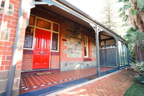 a red front door of a brick house at The Red Door: Expansive Home/Pool/4 BR w Ensuites in Glenelg