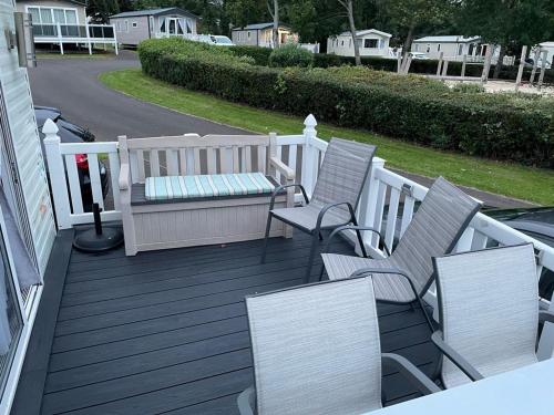 a porch with chairs and a bench on a deck at Luxury modern caravan Seton Sands in Port Seton