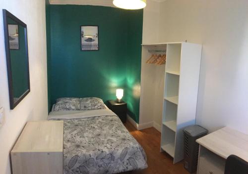 um pequeno quarto com uma cama e uma parede verde em Bel appartement à Dijon 1 em Dijon