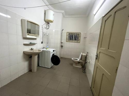 a white bathroom with a toilet and a sink at Appartement spacieux bien situé in Cotonou
