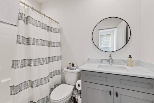 a bathroom with a toilet and a sink and a mirror at Creole House/KING bed/Relax in Cajun Comfort! in Lafayette