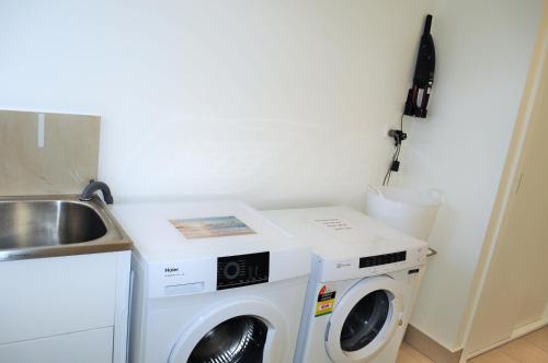 a laundry room with a washing machine and a sink at 100m to Beach&Shop Spacious Pristine One Story Family Home in Batemans Bay