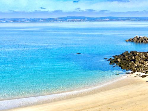 a beach with blue water and rocks at Glaz Ocean in Douarnenez