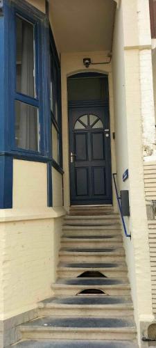 a front door of a building with stairs and a window at Le relax de panne in De Panne