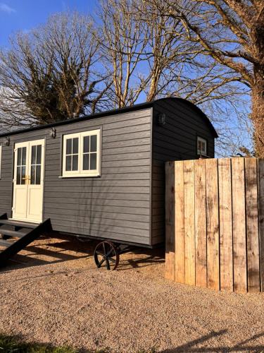 a black tiny house sitting next to a wooden fence at Private Suites in the Burren in Corrofin