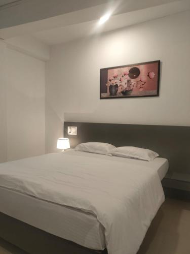 Un dormitorio con una cama blanca con una foto en la pared en Yummly land guest house, en Imphal