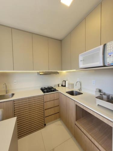 a kitchen with white cabinets and a sink and a microwave at Cosmopolitan 2007 - Apto 800m da Vila Germânica in Blumenau