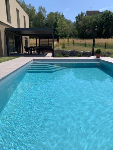 a large blue swimming pool in front of a house at Gîte "Villa Belle Vie" in Labaroche