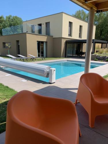 a swimming pool with chairs and a house at Gîte "Villa Belle Vie" in Labaroche