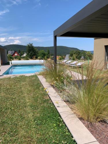 einen Hinterhof mit Pool und Gras in der Unterkunft Gîte "Villa Belle Vie" in Labaroche