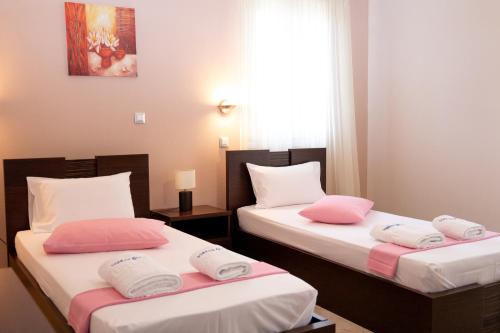 2 Betten in einem Zimmer mit rosa und weißen Kissen in der Unterkunft Villas Gregory in Syvota