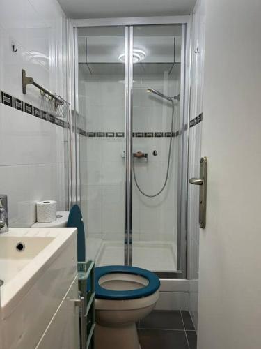 La salle de bains est pourvue d'une douche et de toilettes bleues. dans l'établissement StNicolas1 Frenche Style Appt Bastille, à Paris