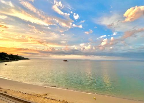 a beach with a cloudy sky and the ocean at Glaz Ocean in Douarnenez