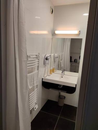 une salle de bain blanche avec un lavabo et un miroir dans l'établissement Appartement quartier Chartrons avec climatisation, à Bordeaux