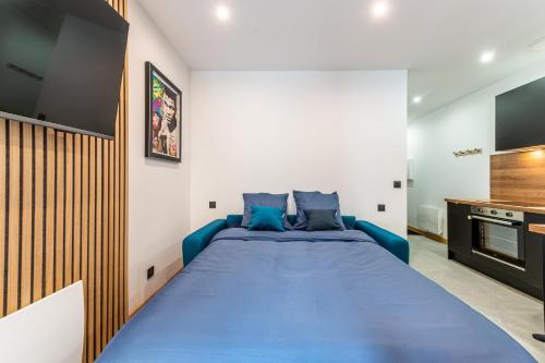 a bedroom with a blue bed and a tv at Studio The Greatest in Moutiers