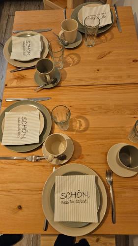 a wooden table with plates and utensils on it at FeelGood Ferienwohnung in Schweina