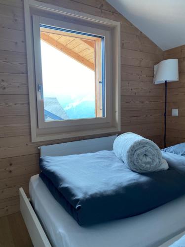 uma cama num quarto com uma janela em Chalet L'Adret, 3,5 pièces dans les combles. em Gryon