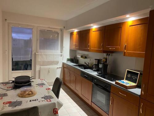 - une cuisine avec des placards en bois, une table et une table dans l'établissement 100m2 3chambres 5km du Carnaval de BASEL Free Wifi, à Huningue