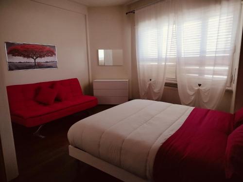 a bedroom with a bed and a red chair and a window at Dandelion home Viareggio centro in Viareggio