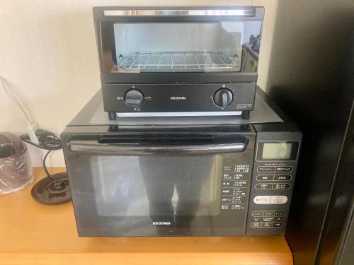 a toaster oven sitting on top of a microwave at Guesthouse NAMAZU in Anan