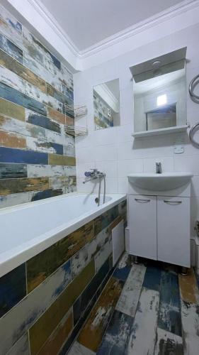 ein weißes Badezimmer mit Waschbecken und Spiegel in der Unterkunft Квартира между правым и левым берегом, рядом с набережной на улице Габдуллина in Astana