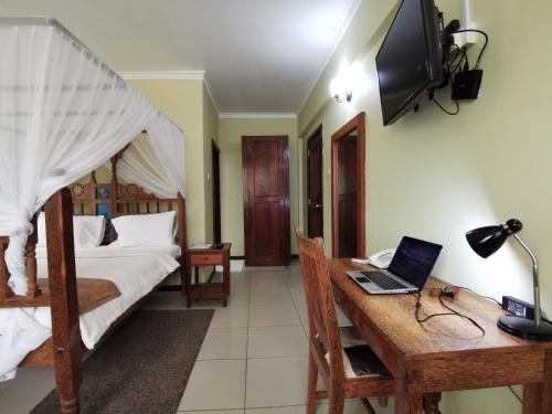 a bedroom with a bed and a desk with a laptop at New Safari Hotel in Chanjani
