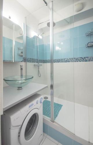 La salle de bains est pourvue d'un lave-linge et d'une douche en verre. dans l'établissement Chez Adeline - Confortable appartement avec piscine et parking, à La Grande Motte