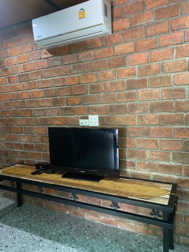 a television sitting on a table in front of a brick wall at แครินโฮมสเตร์ in Koh Lone