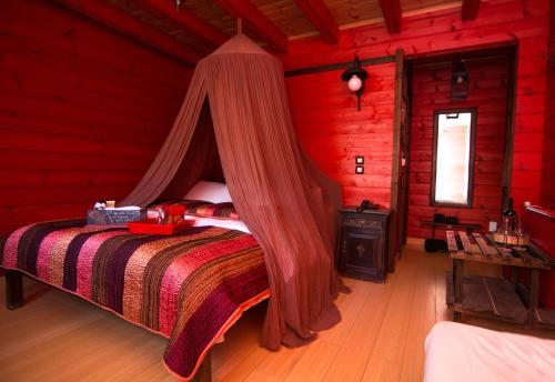a bedroom with a canopy bed in a red room at Colours' Chalet in Synikia Mesi Trikalon