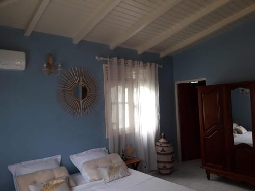 ein blaues Schlafzimmer mit einem Bett und einem Spiegel in der Unterkunft CHEZ Lise et RORO in Pointe-Noire