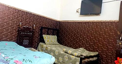 1 dormitorio con 1 cama y TV en la pared en Hotel SleepInn, en Faisalabad