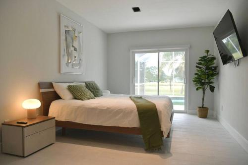 a bedroom with a bed and a tv and a window at Luxury contemporary hidden gem in Lehigh Acres