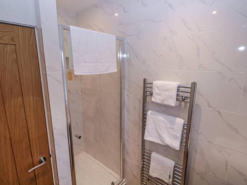 a bathroom with a shower with white towels at Walnut Lodge in Ashbourne
