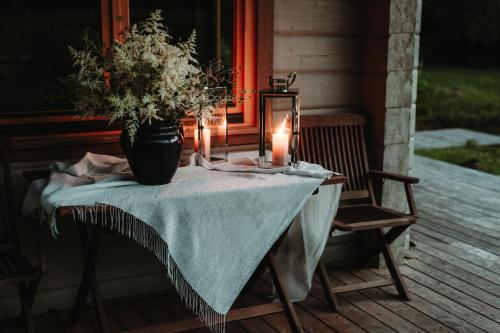 una mesa con un jarrón de flores y velas en un porche en Hortus Paradisum, en Ikšķile