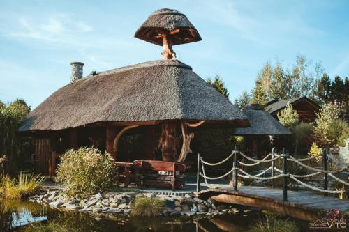 a small hut with a thatched roof and a pond at Kompleks Tawerna Vito - Apartamenty Vito in Czorsztyn