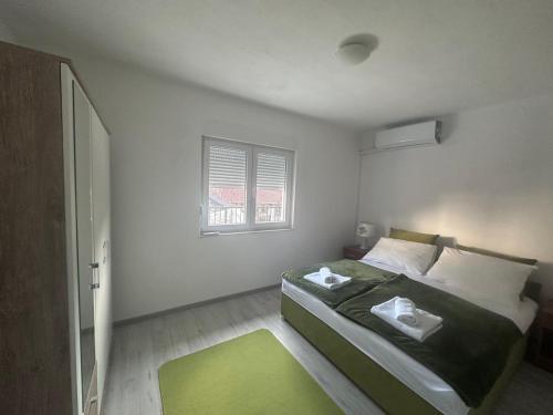 a bedroom with a bed with a green rug and a window at Cuprija _apartments in Stolac