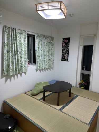 a room with a bed with a table and windows at 一期一会Ⅱ in Osaka