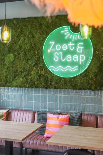 a green sign on the wall of a restaurant with two tables at Zoet & Slaap in Biggekerke