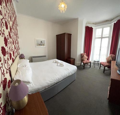 a hotel room with a bed and two chairs at The Embassy Hotel in Great Yarmouth