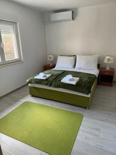 1 dormitorio con 1 cama verde y 2 toallas en Cuprija _apartments, en Stolac