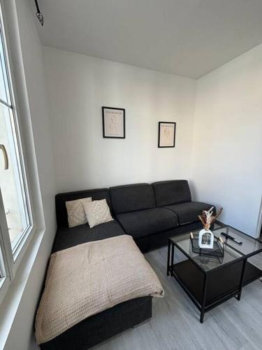 a living room with a black couch and a table at Studio Melun in Melun