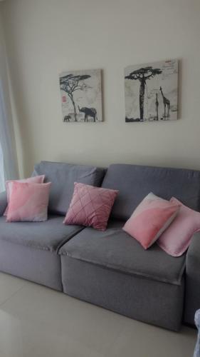 a couch with pink and pink pillows in a living room at Alice in Porto Seguro