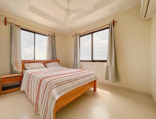 a bedroom with a bed and two windows at Best View Malindi Guest House in Mwembe Maepe