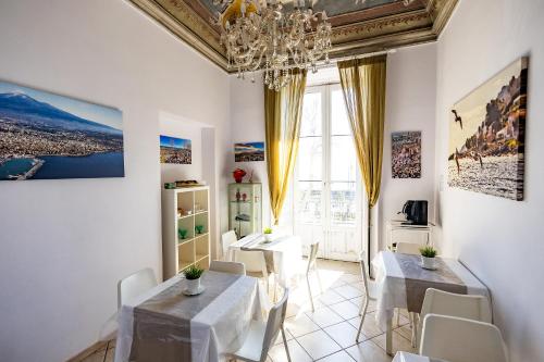 ein Esszimmer mit 2 Tischen und einem Kronleuchter in der Unterkunft Promenade B&B in Catania