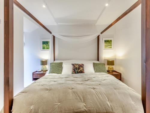 a bedroom with a large bed with two lamps at Midsummer Cottage Retreat in Pilton