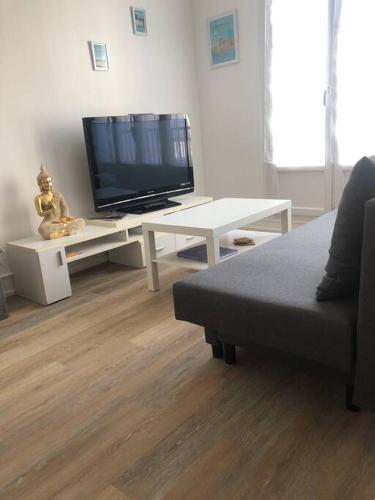 un salon avec une télévision, un canapé et une table dans l'établissement Appartement Lumineux-Coeur de ville & plages, à Concarneau