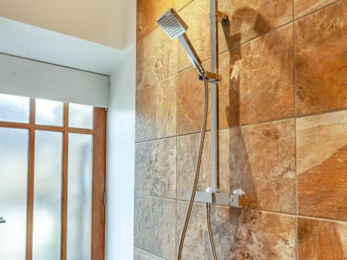 a shower in a bathroom with a stone wall at Midsummer Cottage Retreat in Pilton