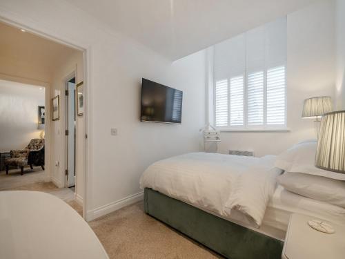 a white bedroom with a bed and a tv on the wall at Luxury Moffat Apartment in Moffat